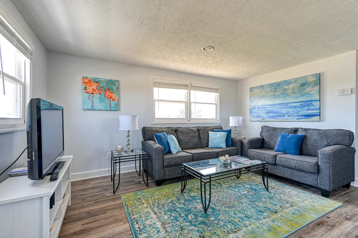 A cozy and inviting living room with a vintage-style sofa set, a central coffee table, charming artwork, and a TV. The space is designed for relaxation, conversation, and making memories, with a welcoming atmosphere that echoes the home’s heritage.